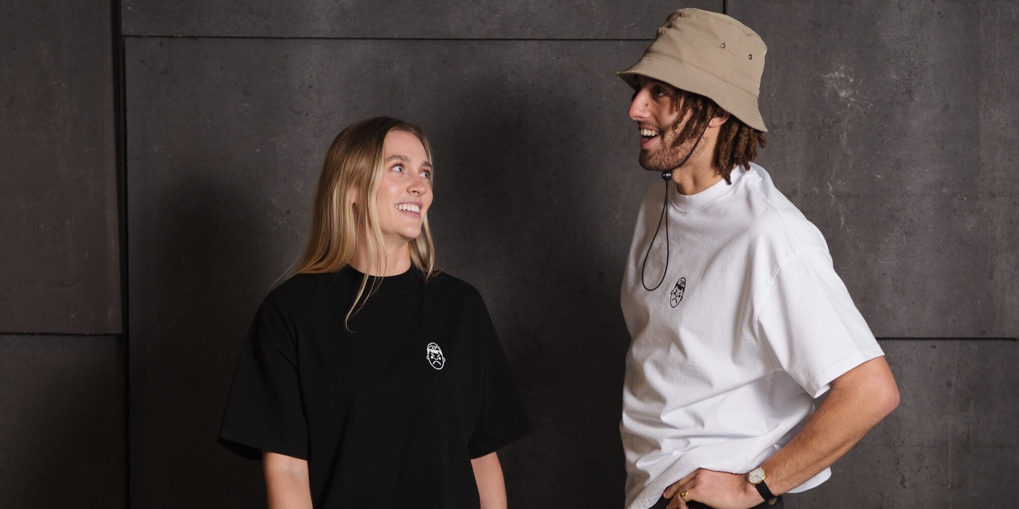 A male and female model wearing oversized t-shirts laughing