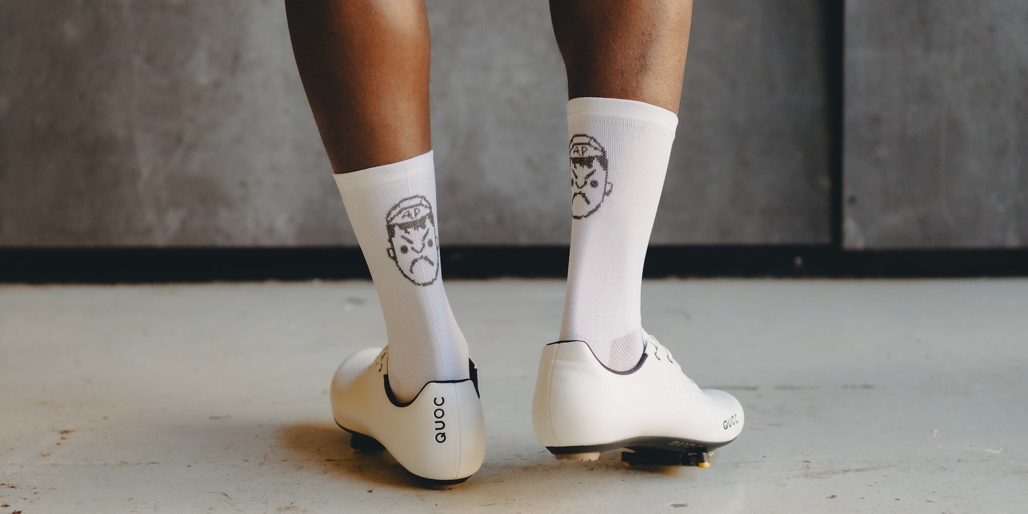 The back of a pair of Angry Pablo white cycling socks and white cycling shoes